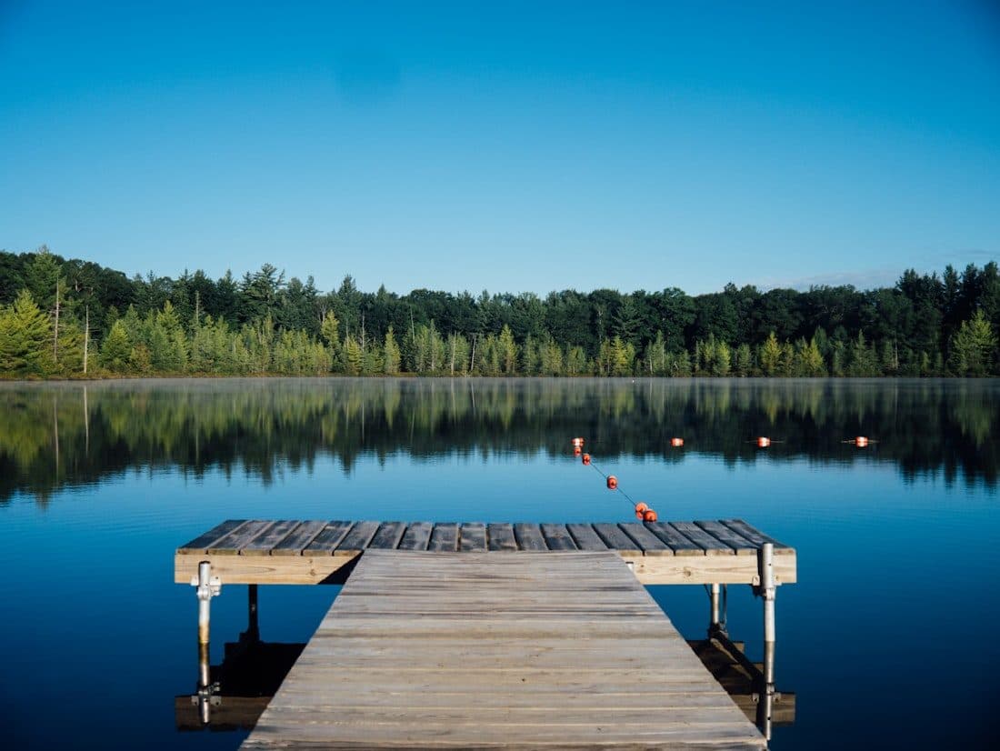 Holzsteg am ruhigen See mit Wald am Ufer
